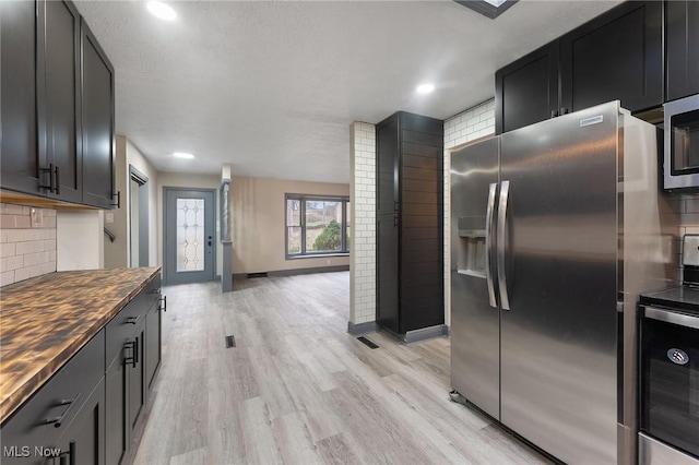 kitchen featuring light hardwood / wood-style floors, appliances with stainless steel finishes, wood counters, and decorative backsplash