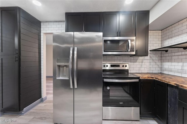 kitchen featuring wood counters, appliances with stainless steel finishes, light hardwood / wood-style floors, and decorative backsplash