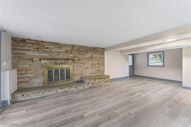 unfurnished living room with a fireplace, a textured ceiling, and light hardwood / wood-style flooring