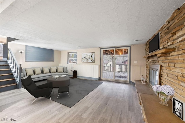 living room with wood-type flooring, a fireplace, and a textured ceiling