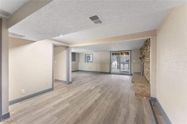 unfurnished living room featuring light wood-type flooring and a textured ceiling