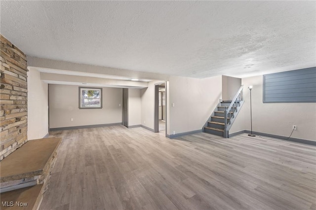 basement with light hardwood / wood-style flooring and a textured ceiling