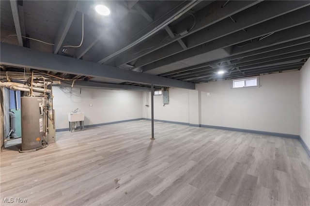 basement with water heater, hardwood / wood-style flooring, sink, and electric panel