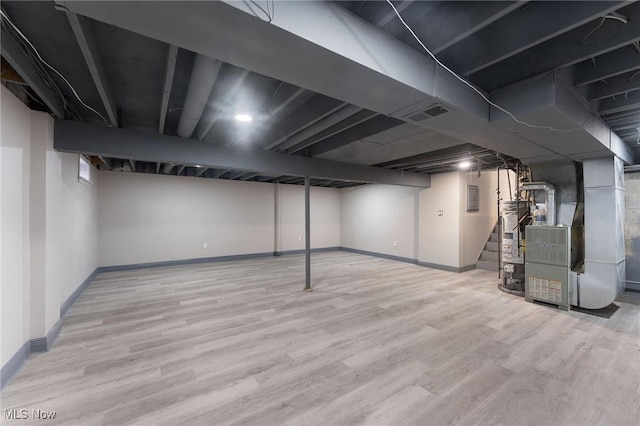 basement with heating unit, water heater, and light hardwood / wood-style flooring