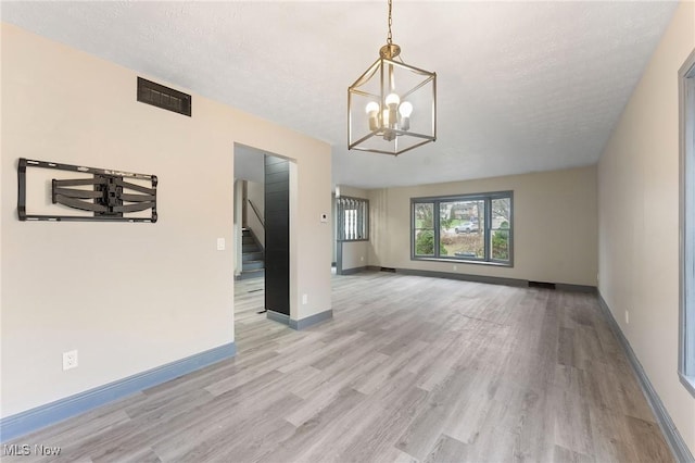 interior space with an inviting chandelier, a textured ceiling, and light wood-type flooring