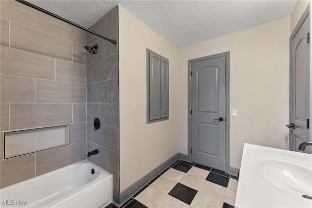 bathroom featuring vanity, tiled shower / bath combo, and a textured ceiling