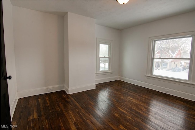 spare room featuring dark wood-type flooring and plenty of natural light