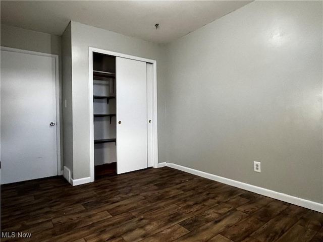 unfurnished bedroom featuring dark wood-type flooring and a closet