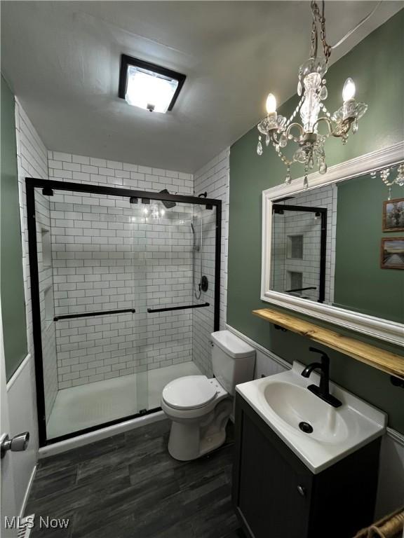 bathroom featuring hardwood / wood-style flooring, vanity, walk in shower, and toilet