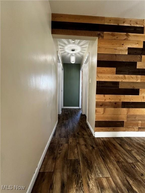 corridor with dark wood-type flooring and wood walls