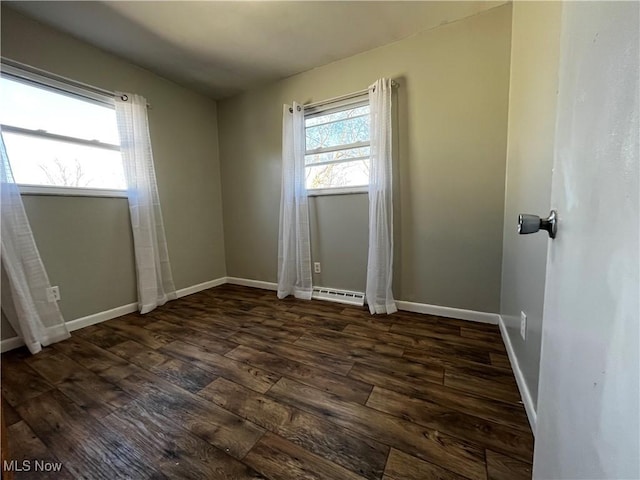 spare room with baseboard heating and dark hardwood / wood-style flooring