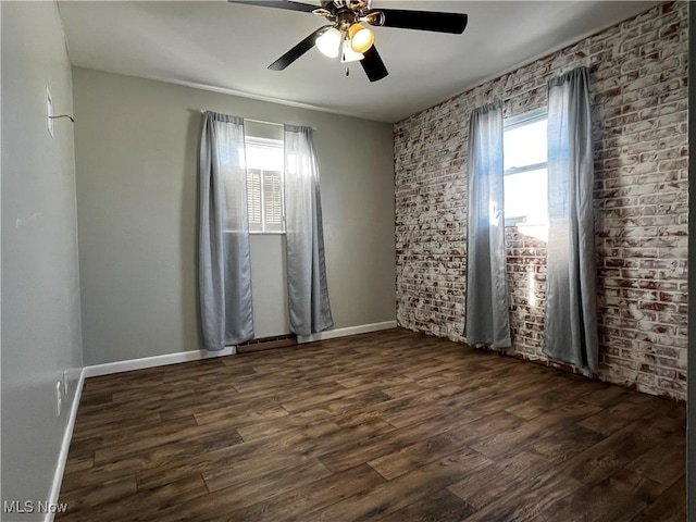 spare room featuring ceiling fan, brick wall, and dark hardwood / wood-style flooring