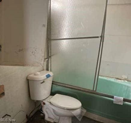 bathroom with bath / shower combo with glass door and toilet