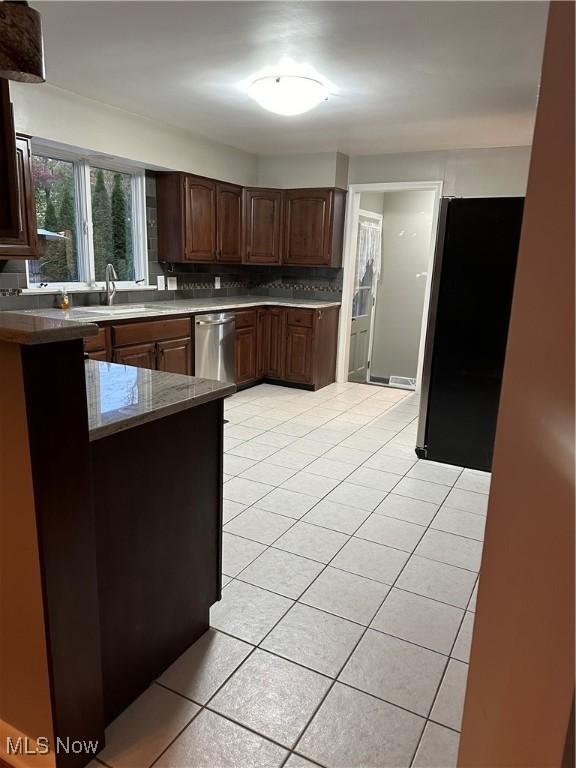 kitchen featuring tasteful backsplash, sink, light tile patterned floors, kitchen peninsula, and stainless steel appliances