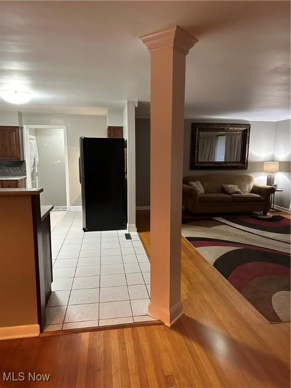 interior space featuring decorative columns, light tile patterned floors, and backsplash