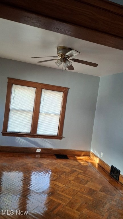 unfurnished room with parquet floors, a healthy amount of sunlight, and ceiling fan