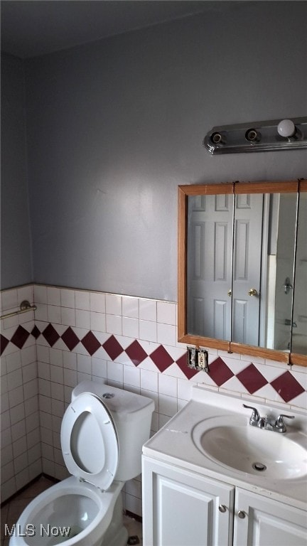 bathroom with vanity, tile walls, and toilet