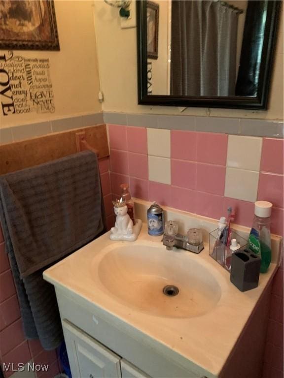 bathroom featuring vanity and tile walls