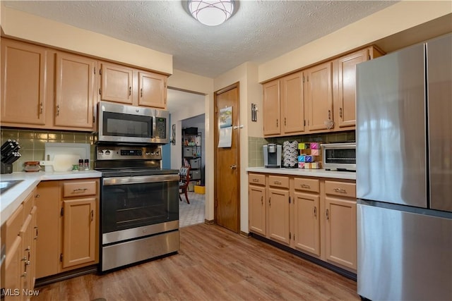 kitchen featuring light brown cabinets, light hardwood / wood-style floors, decorative backsplash, and appliances with stainless steel finishes