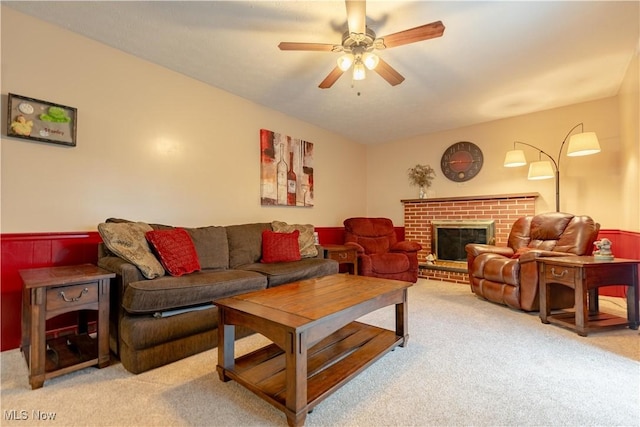 carpeted living room featuring a brick fireplace and ceiling fan