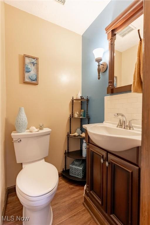 bathroom with vanity, hardwood / wood-style floors, decorative backsplash, and toilet