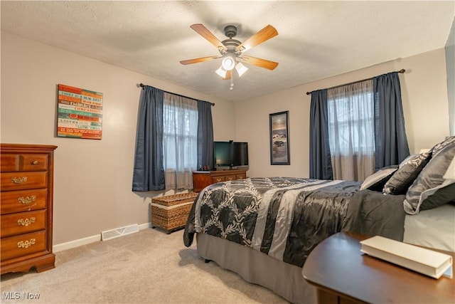 bedroom featuring light carpet, ceiling fan, and a textured ceiling