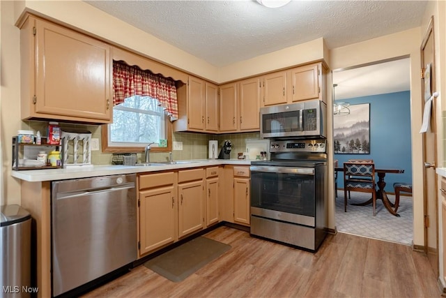 kitchen with tasteful backsplash, appliances with stainless steel finishes, light brown cabinetry, and light hardwood / wood-style floors