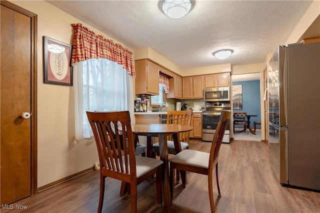 dining space featuring light hardwood / wood-style flooring and a textured ceiling