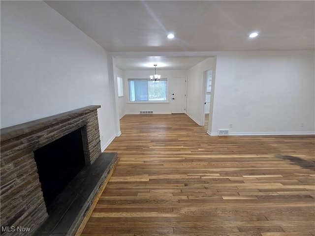 unfurnished living room featuring an inviting chandelier and dark wood-type flooring