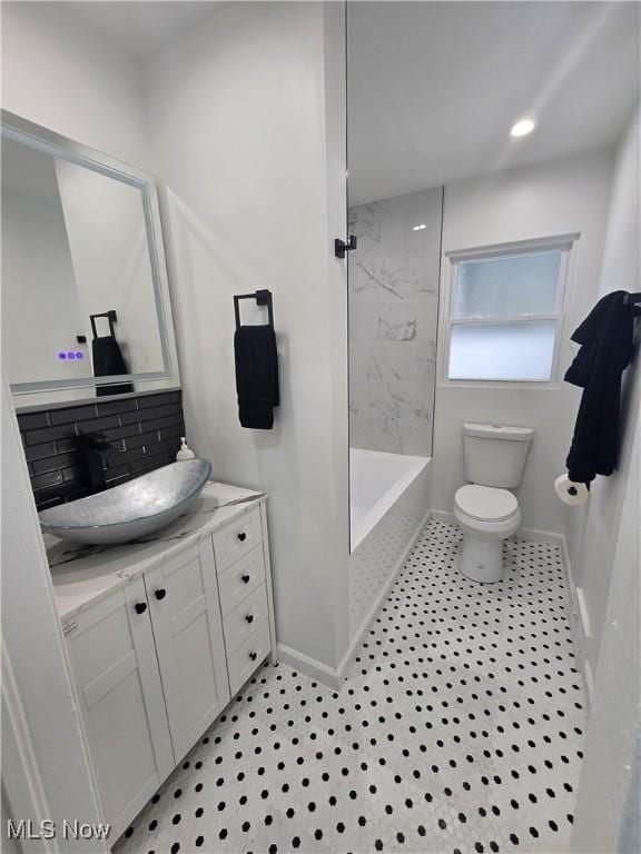 bathroom featuring vanity, backsplash, and toilet