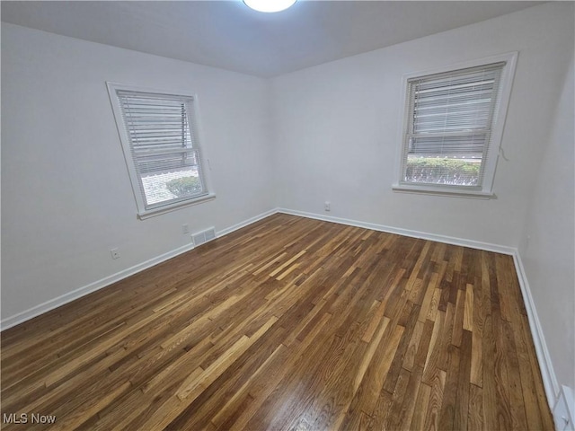 unfurnished room with dark wood-type flooring