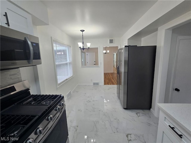 kitchen with a notable chandelier, decorative light fixtures, stainless steel appliances, and white cabinets