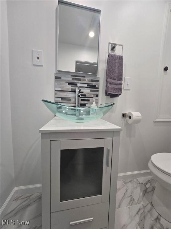 bathroom with vanity, tasteful backsplash, and toilet