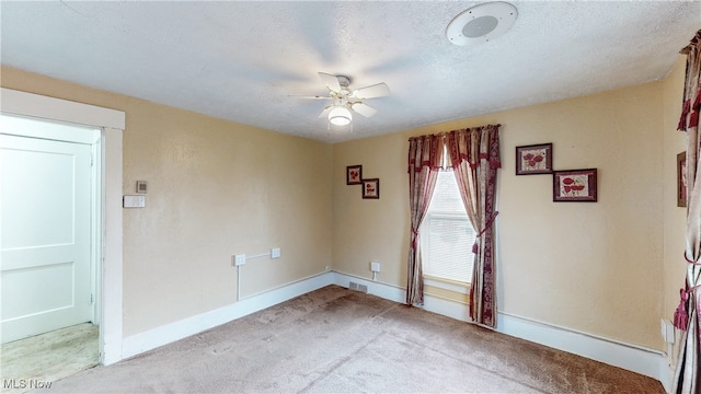 spare room featuring ceiling fan, light colored carpet, and a textured ceiling