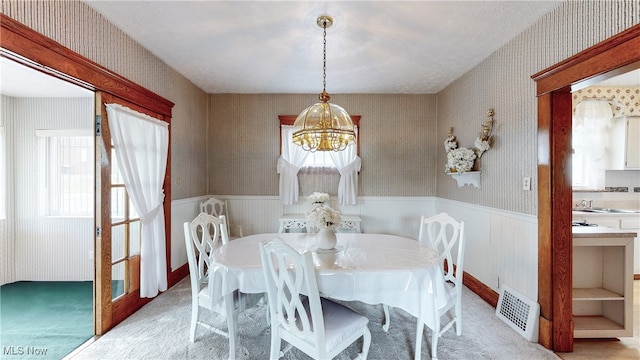 dining room featuring an inviting chandelier, sink, and light carpet