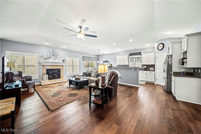 living room with dark wood-type flooring, ceiling fan, and a textured ceiling