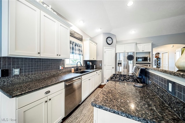 kitchen featuring sink, white cabinetry, stainless steel appliances, tasteful backsplash, and vaulted ceiling