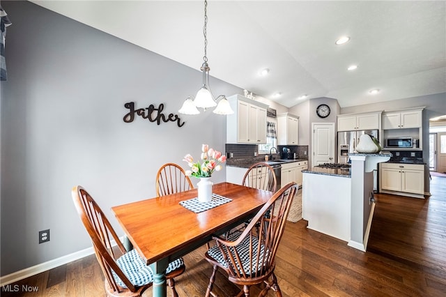 dining area featuring dark wood-type flooring, lofted ceiling, and sink