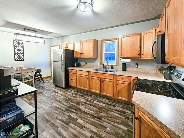 kitchen featuring sink, dark hardwood / wood-style flooring, hanging light fixtures, stainless steel appliances, and a textured ceiling