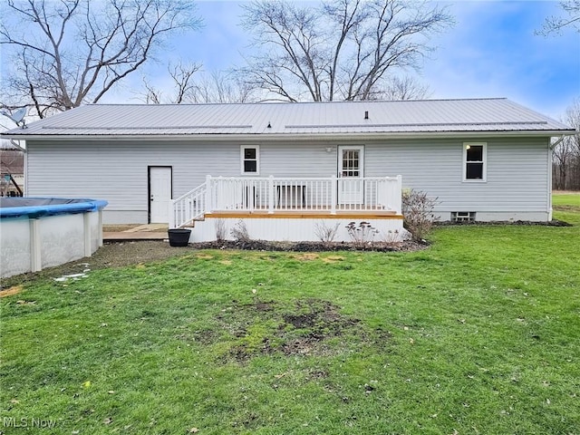 rear view of property featuring a pool side deck and a yard