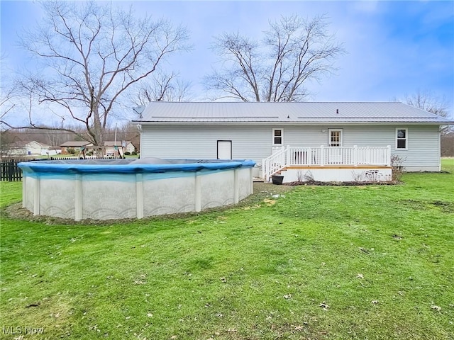 rear view of house featuring a pool side deck and a yard