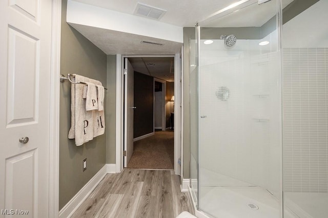 bathroom with hardwood / wood-style flooring and a shower with door