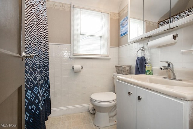 bathroom with vanity, toilet, and tile walls