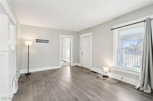 unfurnished room with hardwood / wood-style floors and a textured ceiling