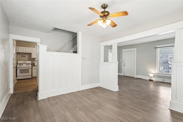 unfurnished living room featuring dark wood-type flooring, decorative columns, and ceiling fan