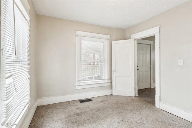 spare room with light carpet and a textured ceiling