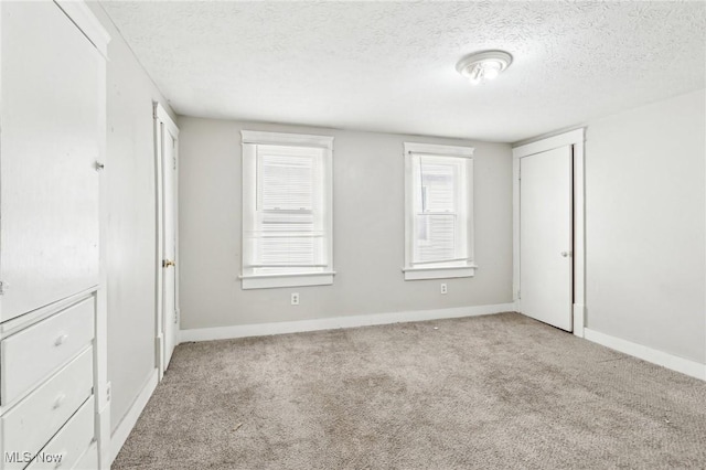 unfurnished bedroom with light colored carpet and a textured ceiling