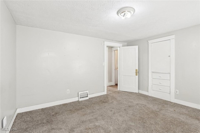 unfurnished bedroom with light colored carpet and a textured ceiling