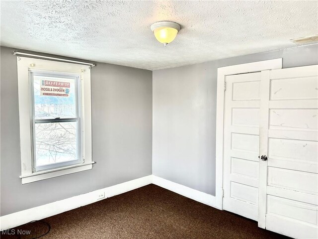 carpeted spare room featuring a textured ceiling