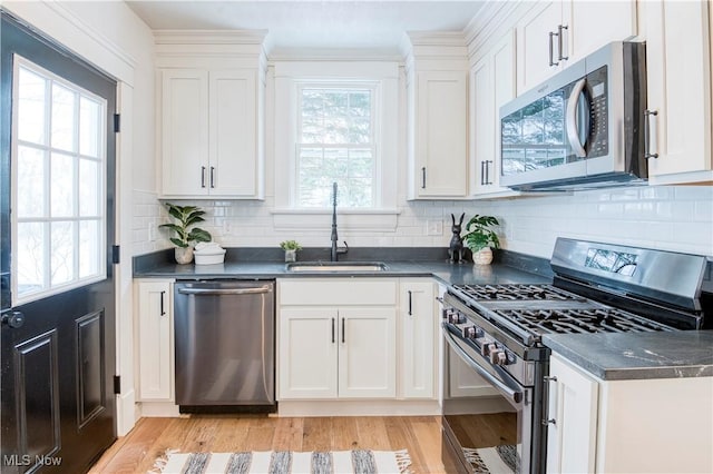 kitchen featuring sink, white cabinetry, stainless steel appliances, tasteful backsplash, and light wood-type flooring